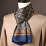 Marineblauwe zijden sjaal met gouden paisleymotieven en bordeauxrode sierrand, op een paspop met beige trui. 12