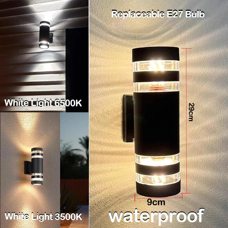 Ronde zwarte cilinderwandlamp met doorzichtige banden en maataanduiding, met voorbeeldfoto's van koud wit en warmer licht tegen een buitenmuur. 9