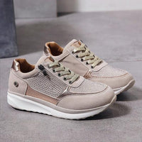 Beige sneakers met goudkleurige veters en steentjes op het bovenwerk, losjes neergezet op een grijze vloer, met zicht op de binnenkant. 2