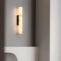 Marmeren wandlamp met donkere afwerking aan een grijze muur boven een witte, gebogen plank naast een witte kolom. 20