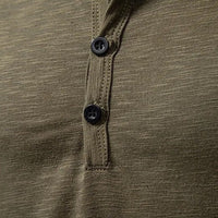 Close-up van de knoopsluiting van het olijfgroene shirt, met zwarte knopen en zichtbare stiksels langs de sluiting. 7