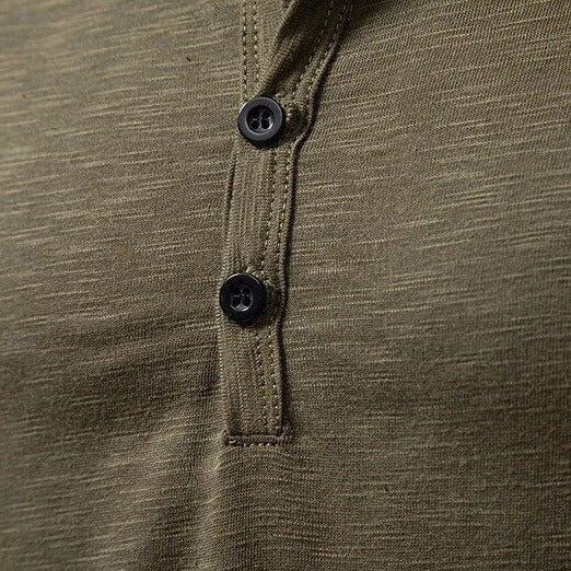 Close-up van de knoopsluiting van het olijfgroene shirt, met zwarte knopen en zichtbare stiksels langs de sluiting. 7