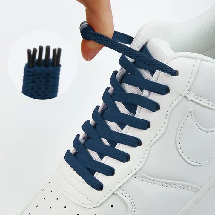 Hand trekt aan een marineblauwe elastische veter op een witte sneaker, met uitvergroot detail van het uiteinde 1