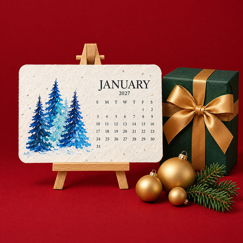 Kalenderkaart januari met blauwe dennenbomen op een houten ezeltje naast een groen cadeau met gouden strik en kerstballen 2