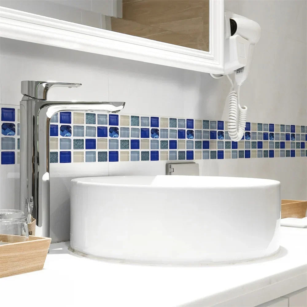 Witte wastafel met chromen kraan en een mozaïekstrook in blauwe en beige tegeltjes op de muur 56