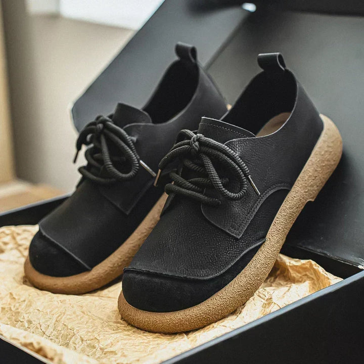 Paar zwarte veterschoenen met lichte rubberen zool, in een open zwarte doos met verpakkingspapier. 12