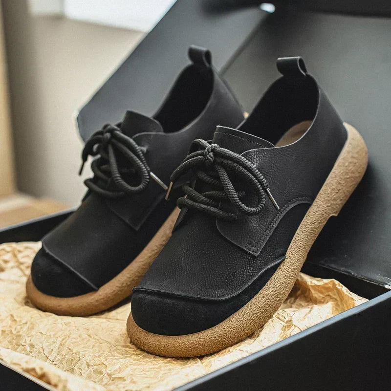 Paar zwarte veterschoenen met lichte rubberen zool, in een open zwarte doos met verpakkingspapier. 12