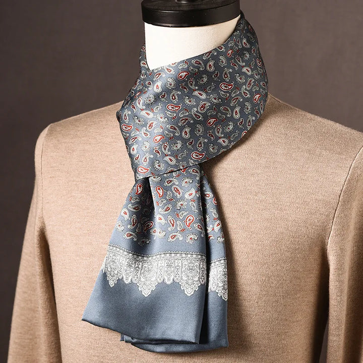 Grijsblauwe zijden sjaal met kleine paisleymotieven in rood en wit en een kantachtige rand, op een paspop met beige trui. 18