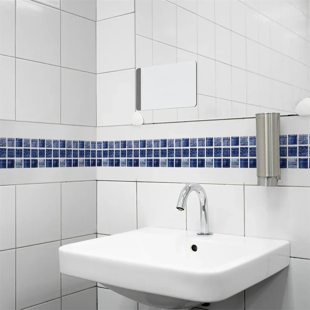 Blauwe mozaïekstrook op witte badkamertegels boven een wandwastafel met chromen kraan 15