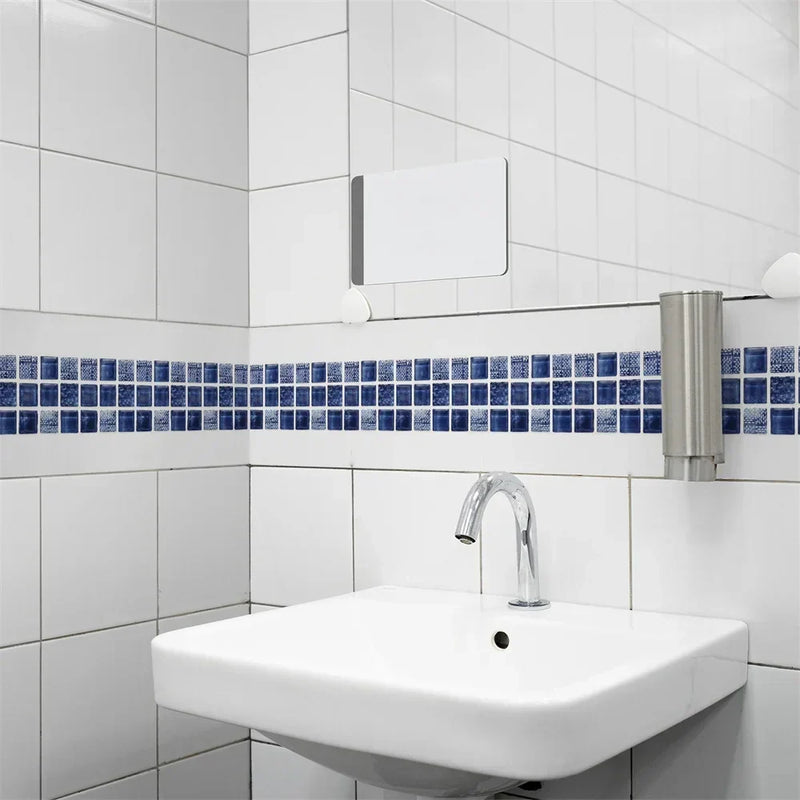 Blauwe mozaïekstrook op witte badkamertegels boven een wandwastafel met chromen kraan 15