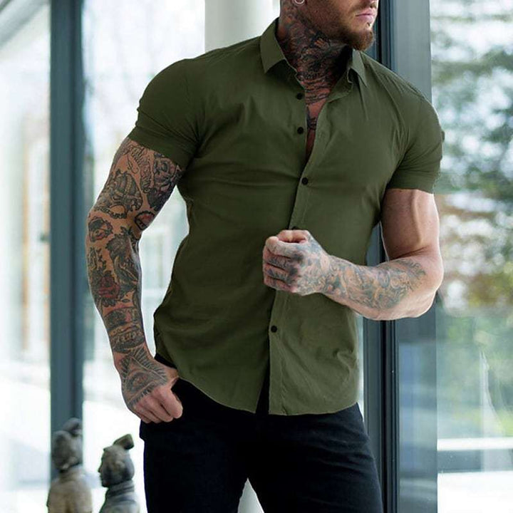 Groen overhemd met puntkraag, gedragen door een getatoeëerde man in een zwarte broek voor een groot raam. 5