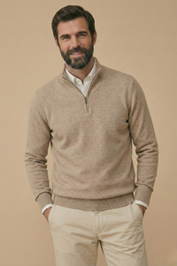 Glimlachend model in beige gemêleerde trui met halve rits, handen in de zakken van een beige broek 6