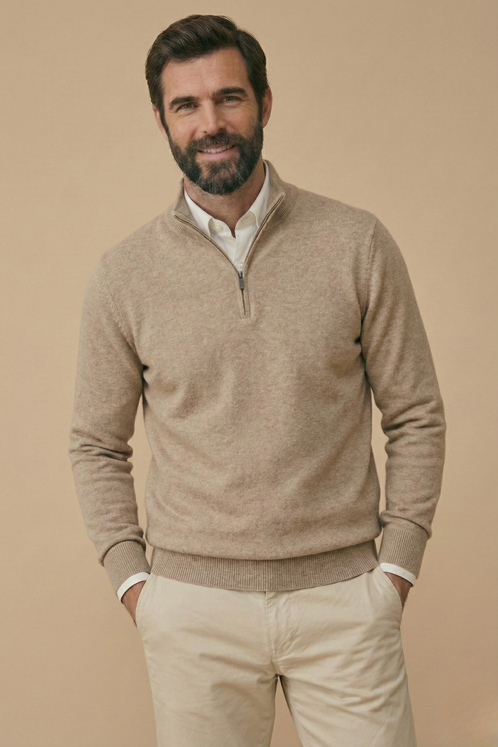 Glimlachend model in beige gemêleerde trui met halve rits, handen in de zakken van een beige broek 6