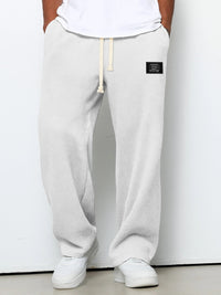 Voorkant van de wafelgebreide broek in een lichte, bijna witte tint, gedragen met wit shirt en witte sneakers. 2