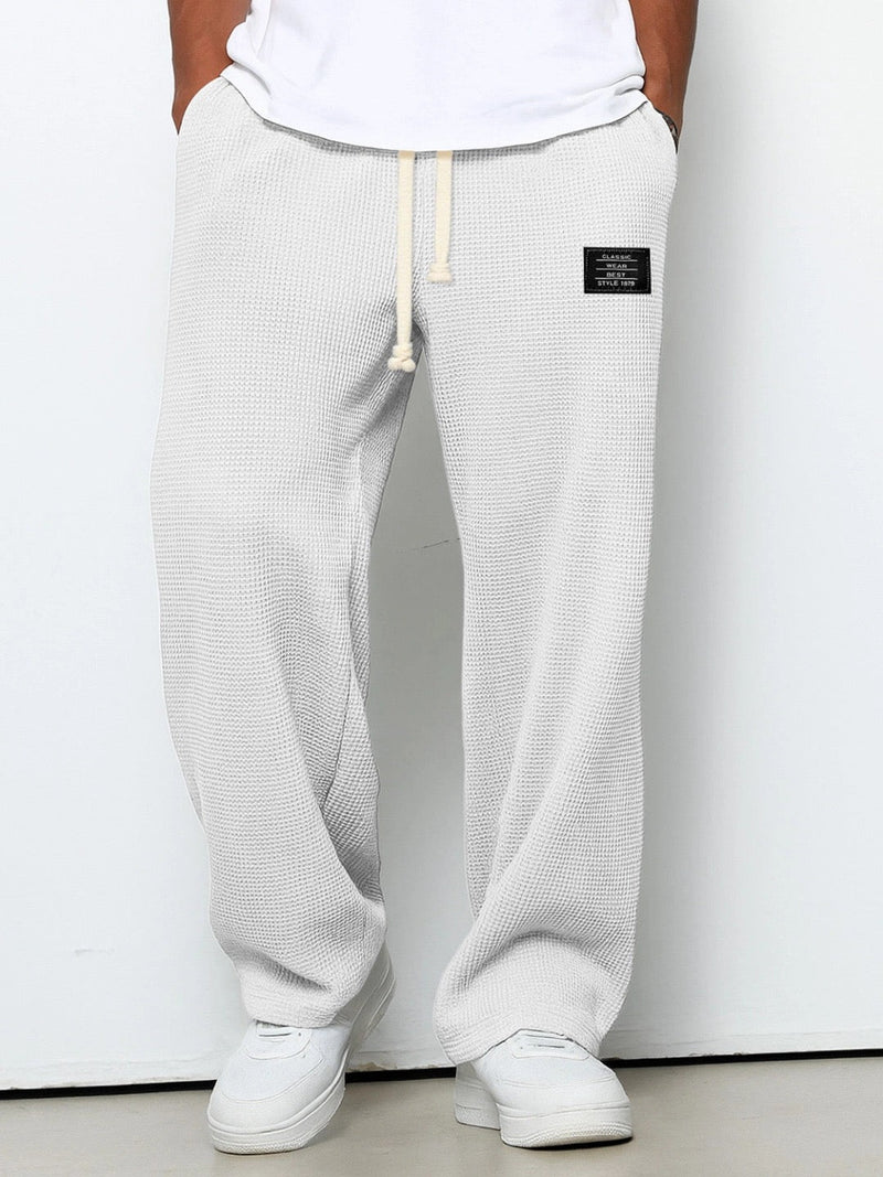 Voorkant van de wafelgebreide broek in een lichte, bijna witte tint, gedragen met wit shirt en witte sneakers. 2