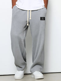 Voorkant van de wafelgebreide broek in lichtgrijs, gedragen met wit shirt, witte sneakers en handen in de zakken. 3