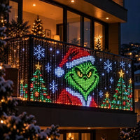 Balkonhek met lichtgordijn dat een groen gezicht met kerstmuts toont, omringd door kerstbomen en sneeuwvlokken 9