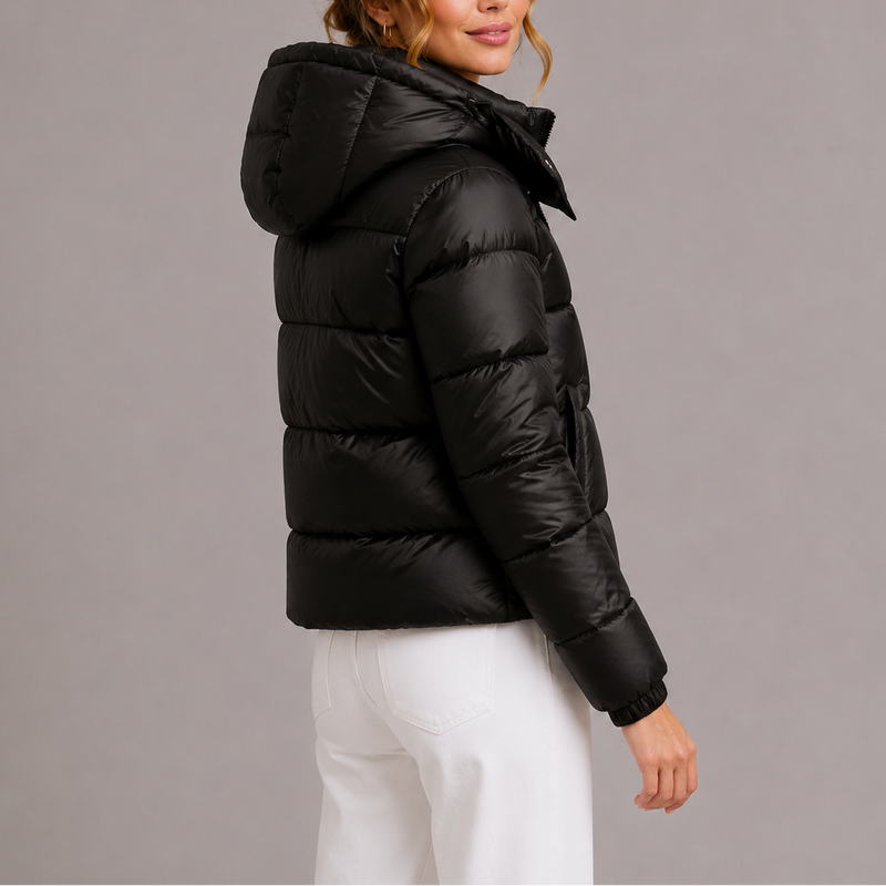 Zwart gewatteerd jack met capuchon, schuin van achteren gezien op een model met witte broek 4
