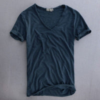 Voorkant van het shirt in donkerblauw op een grijze ondergrond, met V-hals, omgeslagen mouwen en opgerolde zoom. 5