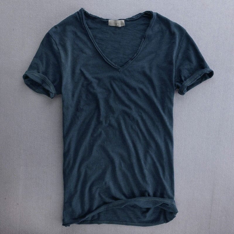 Voorkant van het shirt in donkerblauw op een grijze ondergrond, met V-hals, omgeslagen mouwen en opgerolde zoom. 5