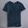 Voorkant van het shirt in donkerblauw op een grijze ondergrond, met V-hals, omgeslagen mouwen en opgerolde zoom. 5