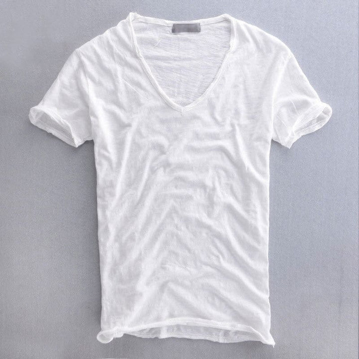 Voorkant van het shirt in wit op een grijze ondergrond, met diepe V-hals en omgeslagen korte mouwen. 2