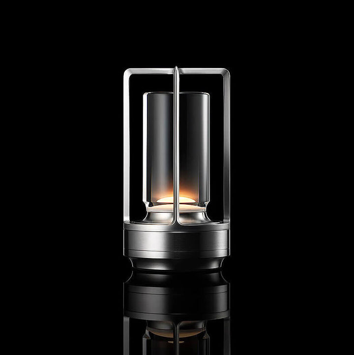 Zilverkleurige lamp met open frame en glazen cilinder, brandend tegen een zwarte achtergrond met spiegeling. 10
