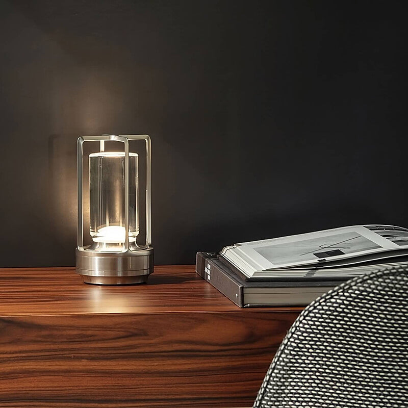 Zilverkleurige lamp brandt op een houten dressoir naast opengeslagen boeken, voor een donkere muur. 5