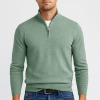 Man draagt een saliegroene trui met halve ritssluiting, wit shirt eronder, zwarte riem en spijkerbroek. 5