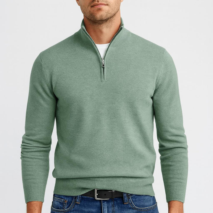Man draagt een saliegroene trui met halve ritssluiting, wit shirt eronder, zwarte riem en spijkerbroek. 5