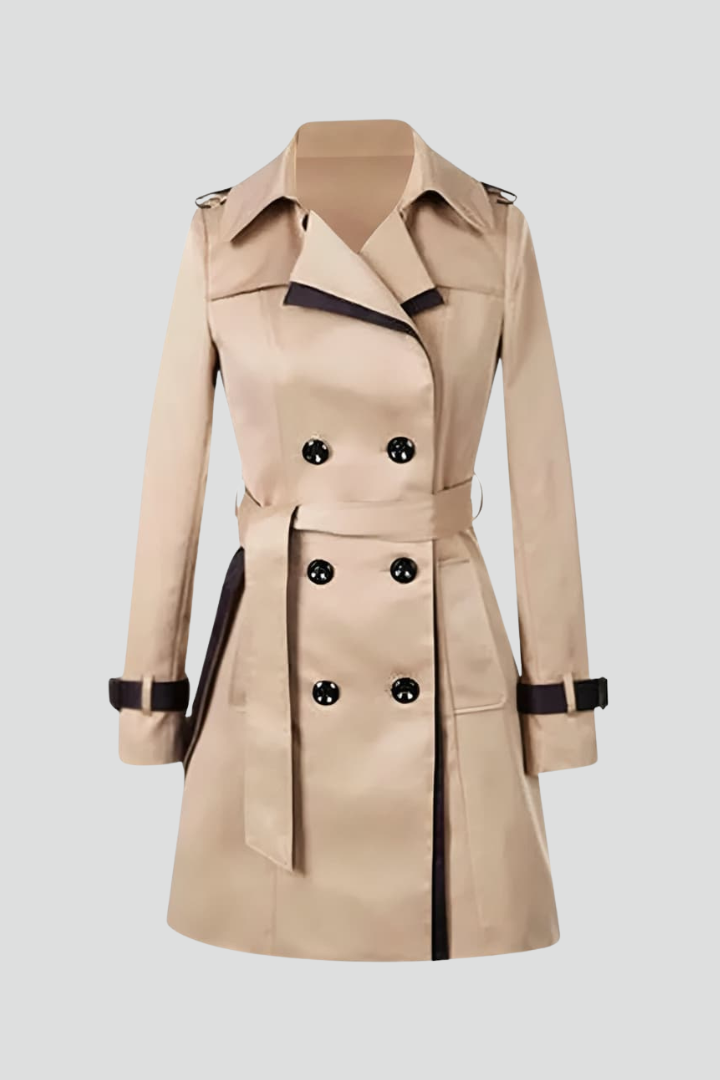Beige dubbelrijige trenchcoat met donkere bies, ceintuur en bandjes aan de mouwen, los neergelegd op een lichte achtergrond. 1