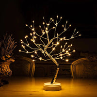 Verlichte boomlamp met warme lampjes op een tafel naast een vaas met gedroogde bloemen 2