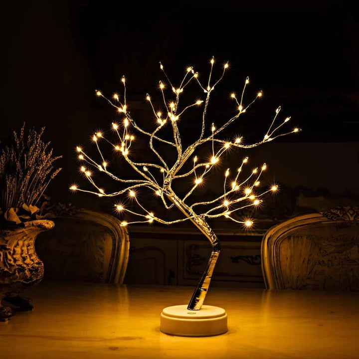 Verlichte boomlamp met warme lampjes op een tafel naast een vaas met gedroogde bloemen 2