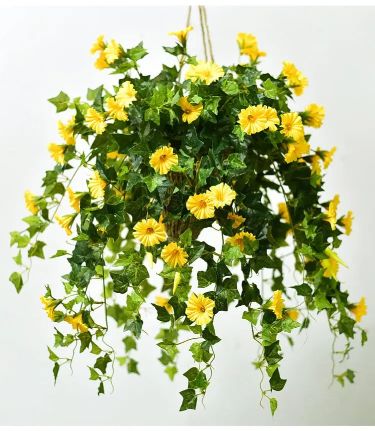 Hangende bos gele kunstbloemen met donkergroene klimopbladeren aan touwen, gefotografeerd tegen een lichte achtergrond. 2