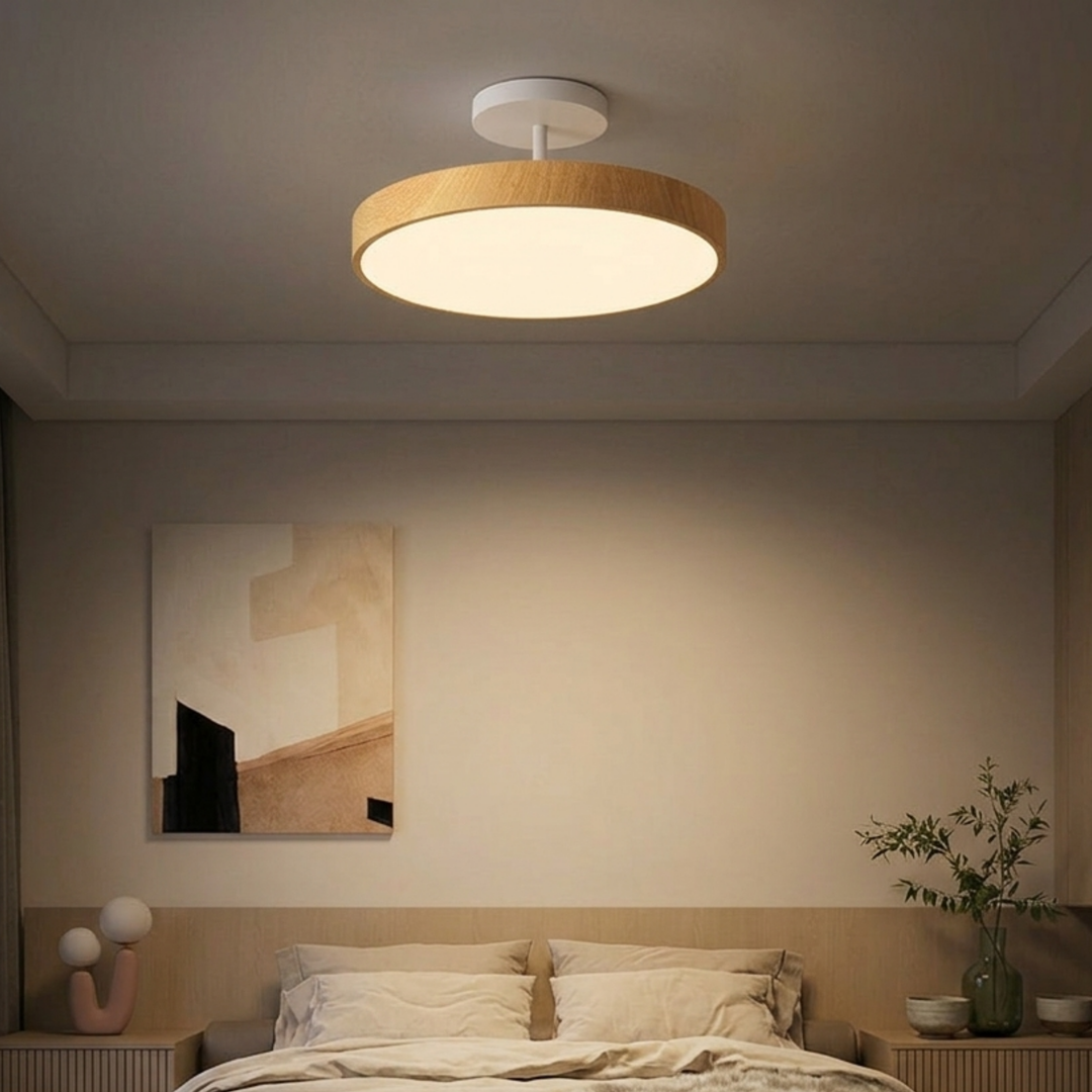 Lichte houtlook plafondlamp met witte steun boven een slaapkamerbed met beige beddengoed en een schilderij aan de muur. 7