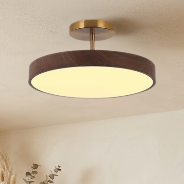 Dezelfde lamp met donkere houtlook rand en goudkleurige steun, brandend aan het plafond, gezien iets van opzij. 3