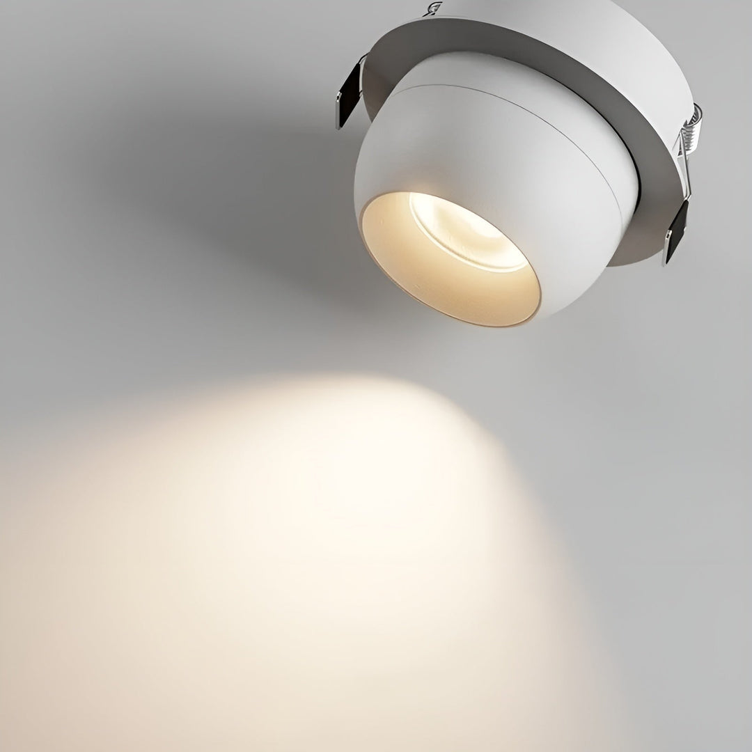 Close-up van een witte inbouwspot met veerklemmen aan de rand en een zachte lichtvlek op het plafond 4