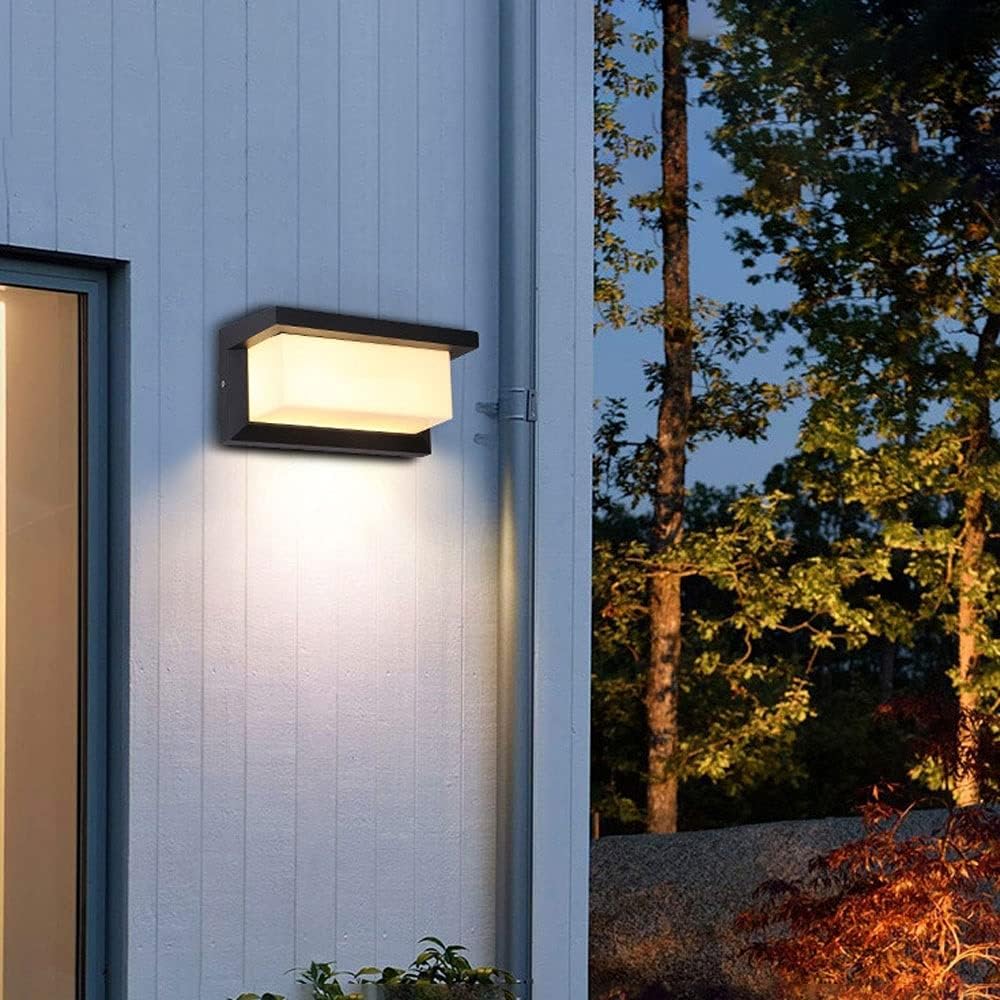 Wandlamp aan een lichte houten buitenwand met een regenpijp, met bomen in de avondschemering 6
