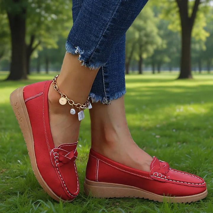 Rode instaploafers met witte stiksels en lichtbruine zool, gedragen op het gras in een park. 7