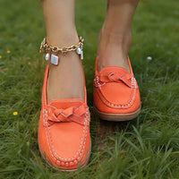 Oranje loafers met gevlochten sierband gedragen op het gras, met een gouden enkelbandje met parels. 4