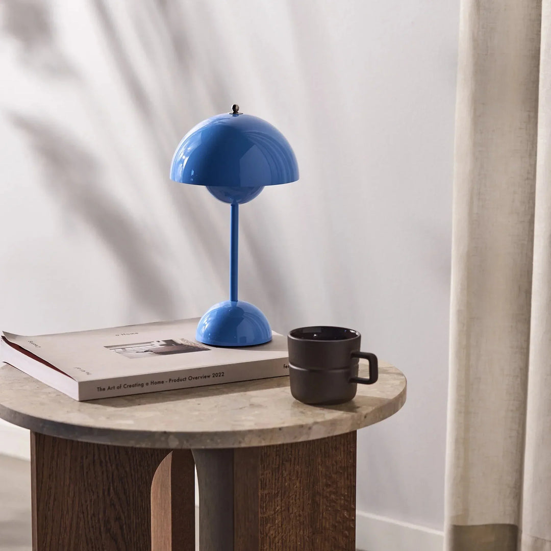 Heldere blauwe lamp op een ronde bijzettafel met een boek en een donkere mok 33