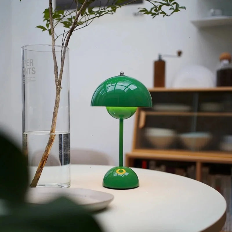 Felgroene lamp met halfronde kap op een ronde witte tafel naast een glazen vaas met tak 43