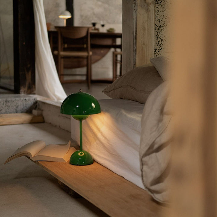 Groene lamp brandt op een houten plank naast een bed, met een opengeslagen boek ernaast 37