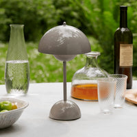Taupekleurige lamp op een buitentafel met karaf, glazen met streeppatroon, fruitschaal en fles 32