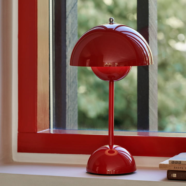 Glanzende rode lamp op een vensterbank voor een rood raamkozijn, naast een stapel boeken 29
