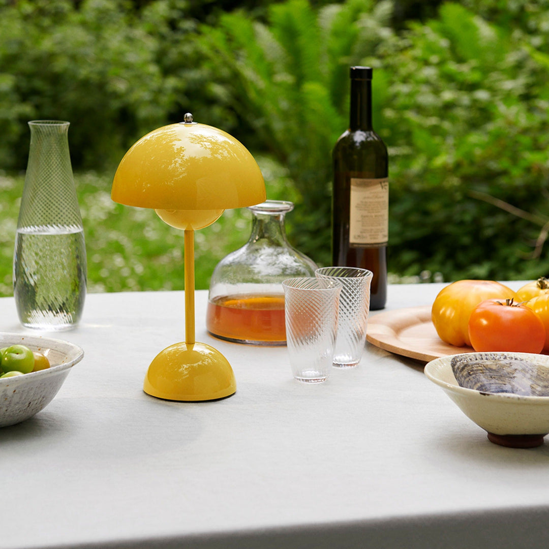 Glanzende gele lamp op een buitentafel met glazen, een karaf, een wijnfles en tomaten 24