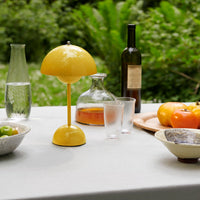 Glanzende gele lamp op een buitentafel met glazen, een karaf, een wijnfles en tomaten 24