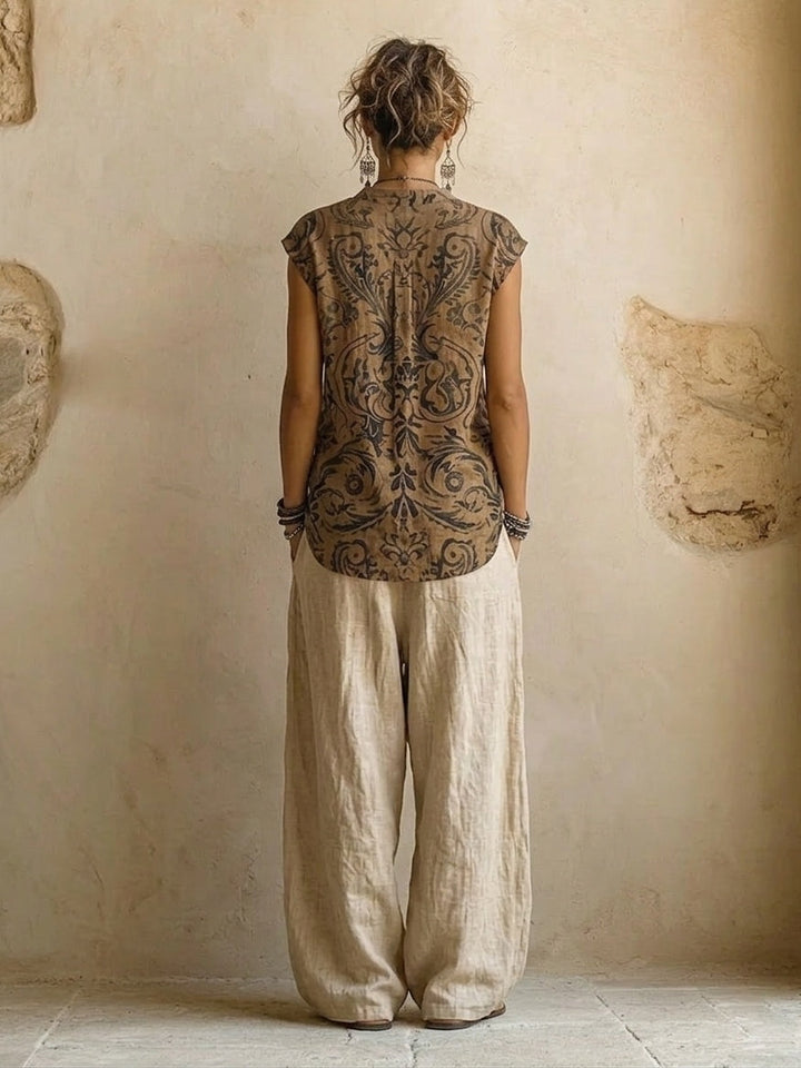 Achteraanzicht van de mouwloze top met groot sierpatroon en de ruim vallende beige linnen broek 3