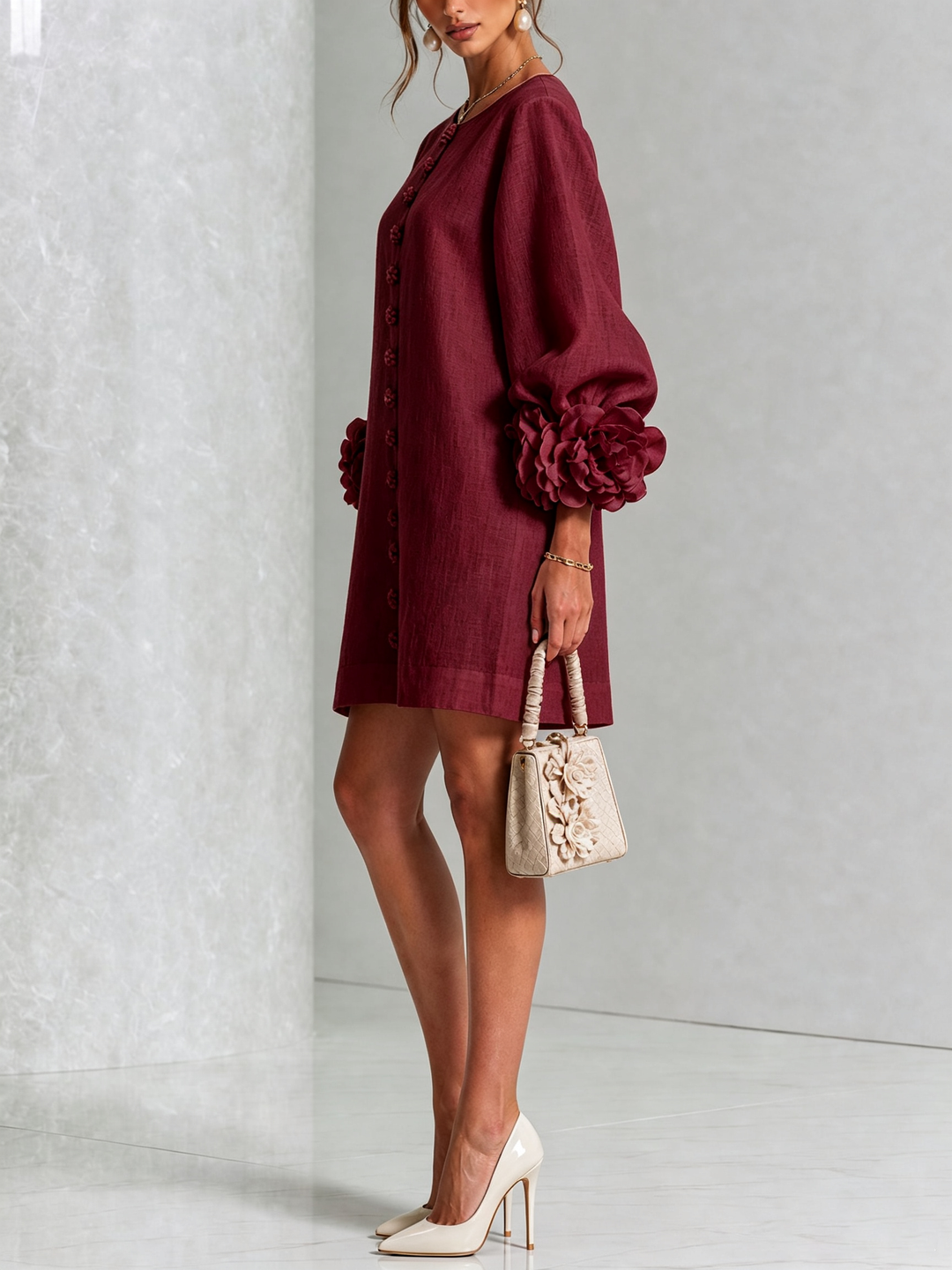 Zijaanzicht van bordeauxrode mini-jurk met pofmouw en roosmanchet, model met beige handtasje met bloemen en crèmekleurige pumps. 36