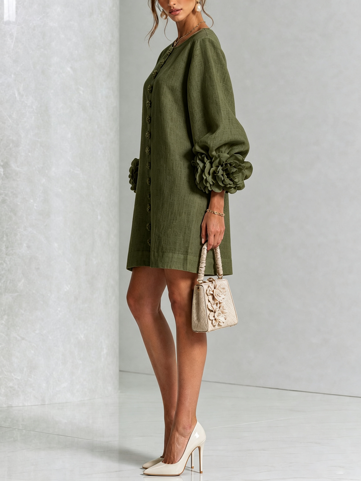 Groene jurk van opzij gefotografeerd op een model met beige handtas en lichte pumps, roosmanchet duidelijk zichtbaar. 8